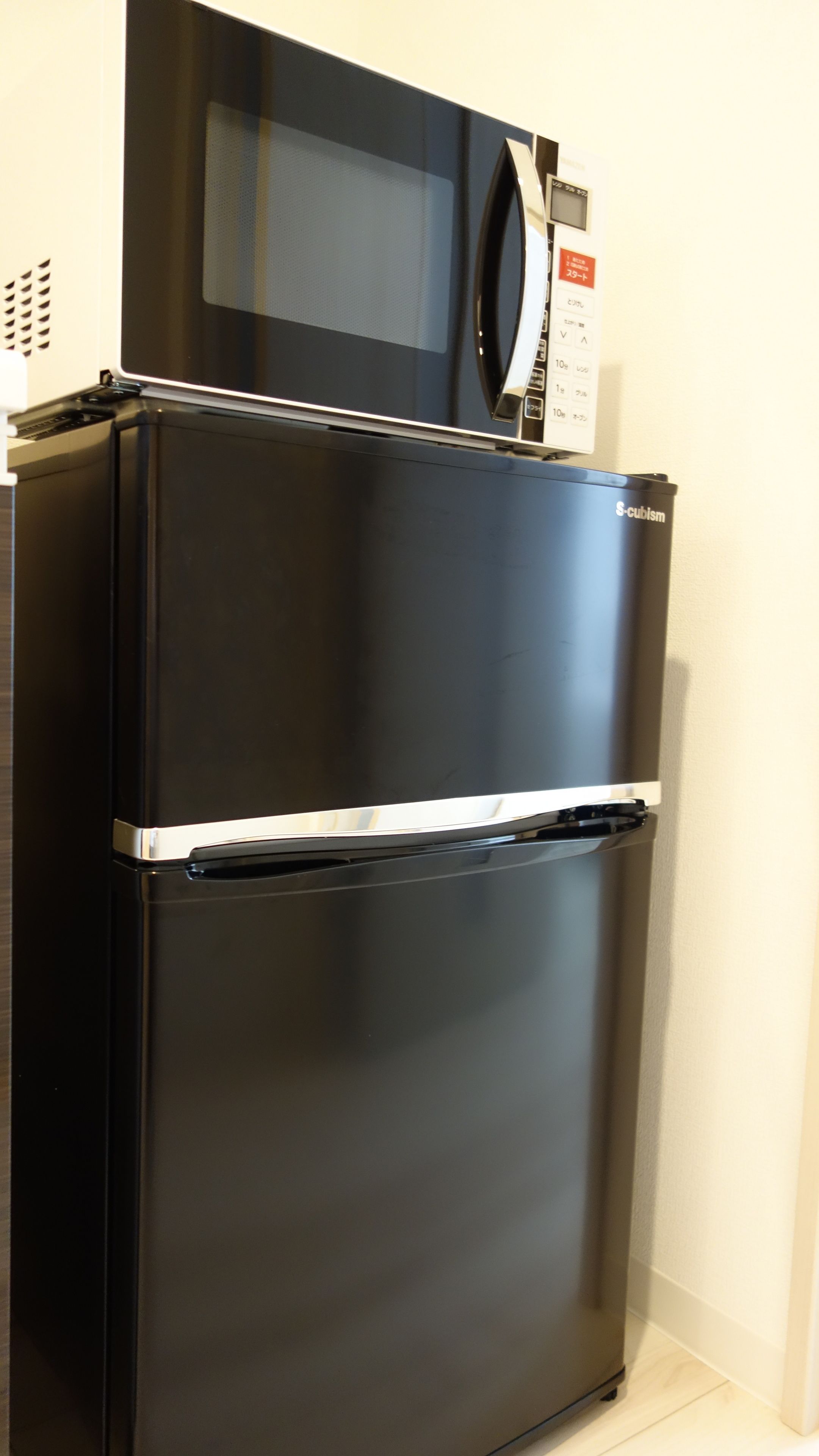 A black refrigerator with a microwave on top, a control panel, and a brand name.