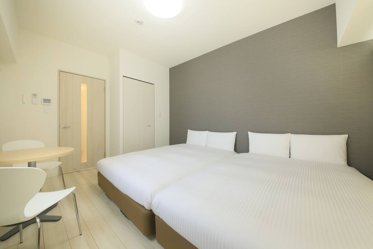A modern hotel room with a large bed, a small table, and a chair.