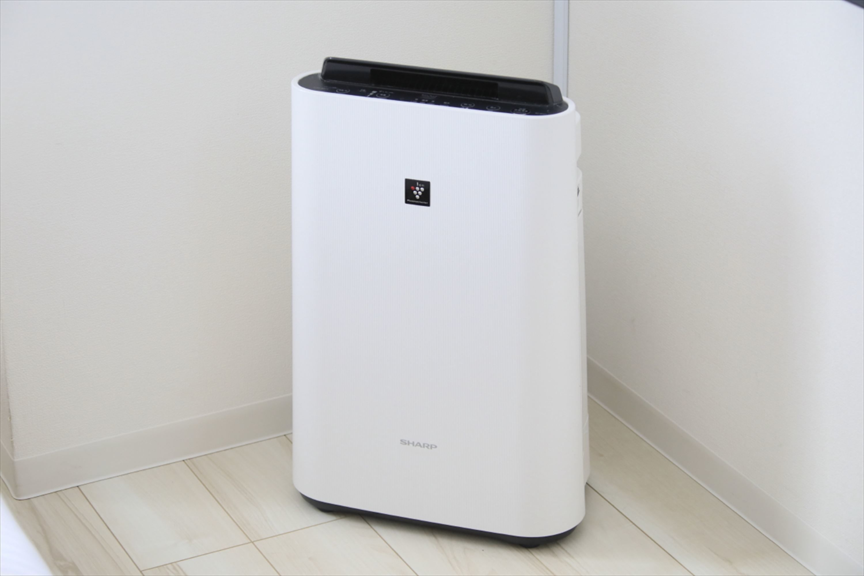 A white, modern air purifier with a black top panel and the brand name 'SHARP' visible on the front.