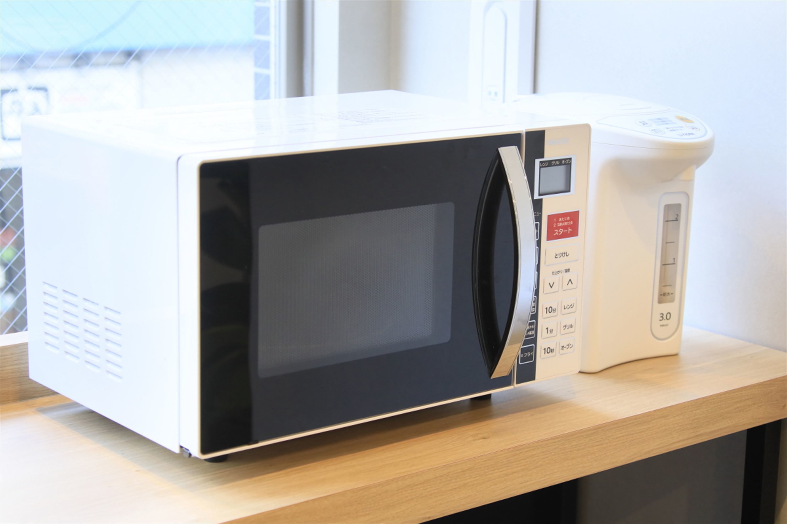 A microwave oven with a digital display and a control panel on a wooden countertop.