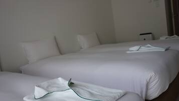 A hotel room with two beds, each with white linens and pillows.