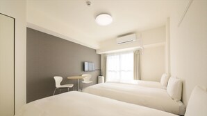 Quarto de hotel com duas camas, uma pequena escrivaninha, uma cadeira, uma televisão de tela plana e uma janela com cortinas.