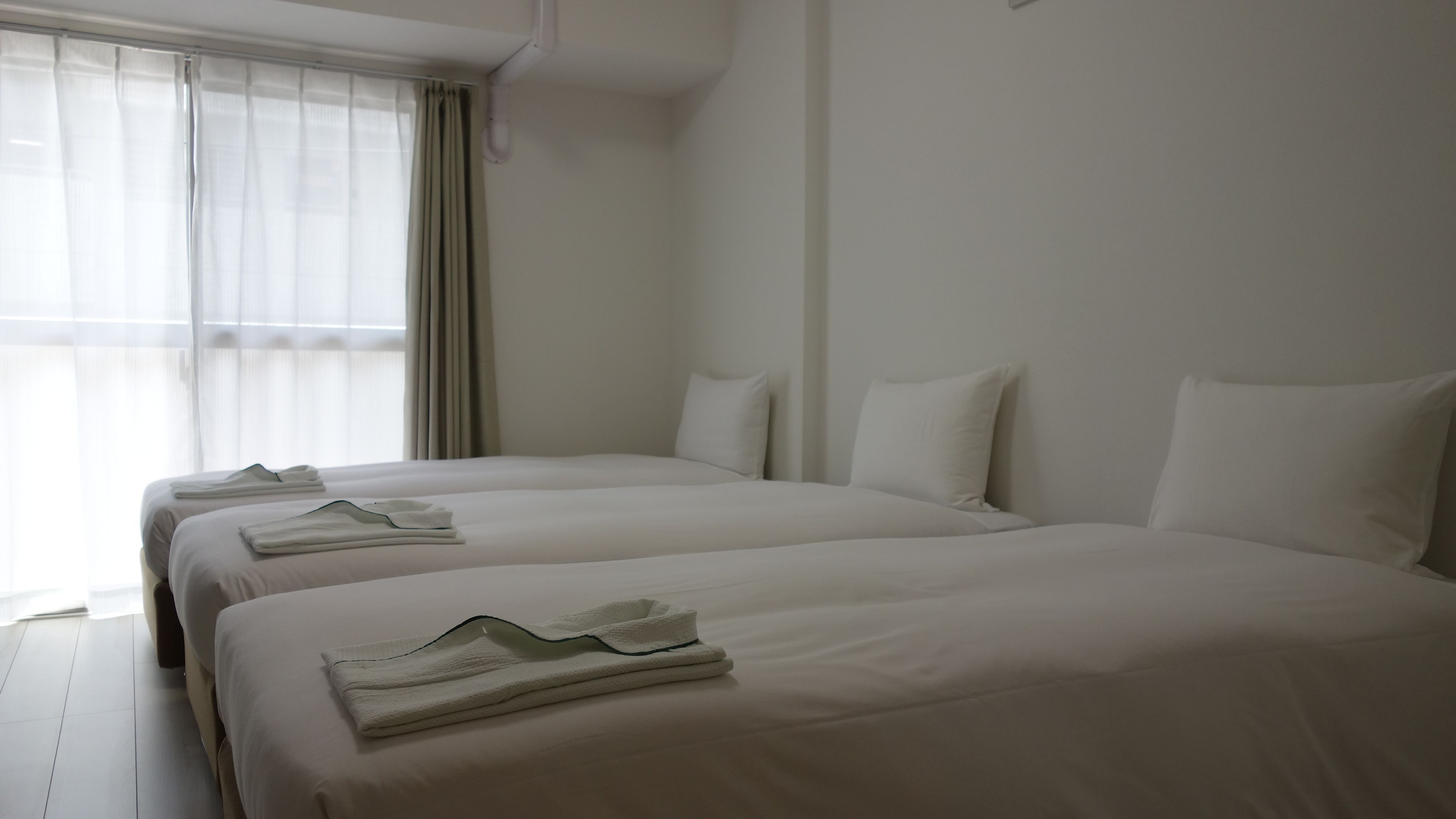 Una habitación de hotel con dos camas individuales, cada una con toallas impecablemente dobladas.
