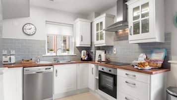 A modern kitchen with white cabinetry, stainless steel appliances, and a wooden countertop.