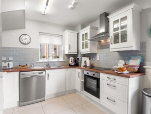 Une cuisine moderne avec des meubles blancs, des appareils en acier inoxydable et un plan de travail en bois.