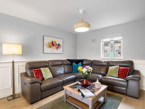 Un salon moderne avec un canapé en cuir, une table basse, un lampadaire et une fenêtre avec des stores.