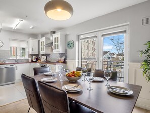 Une cuisine moderne avec un coin repas, de grandes fenêtres et une vue sur les immeubles.