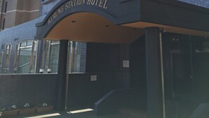 Ein moderner Hotel-Eingang mit einem Schild, auf dem 'Kurume Station Hotel' steht.