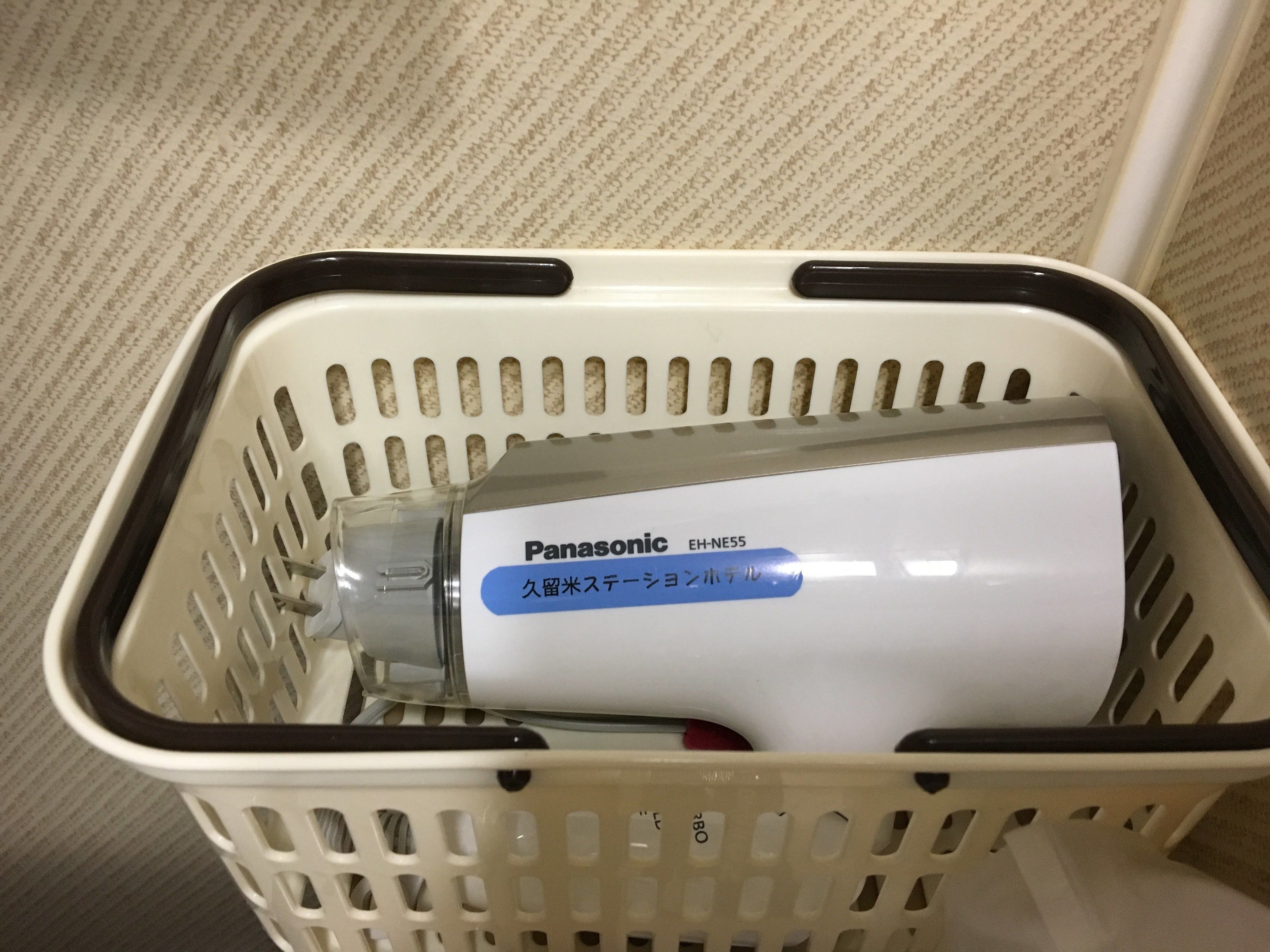 Una cesta de plástico blanco con borde negro que contiene una aspiradora Panasonic EH-NE55 blanca.