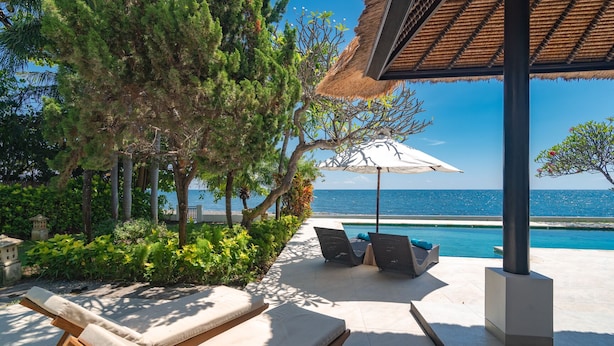 A poolside area with lounge chairs and a pergola providing shade.