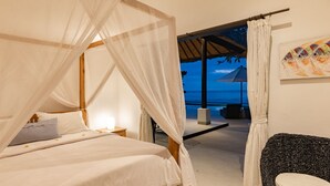 A bedroom with a bed, a nightstand, a chair, and a view of the ocean.