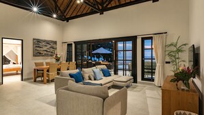A spacious living area with a high ceiling, large windows, and a view of the outdoors.