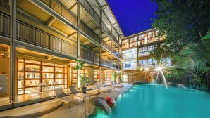 A multi-story hotel with a swimming pool, lounge chairs, and a bar area. - Holiday Park Hotel (Koh Samui)