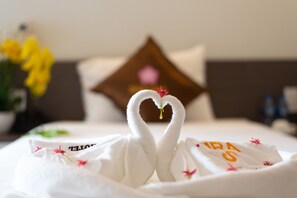 A bed with a heart-shaped towel arrangement and a pillow with a floral design.