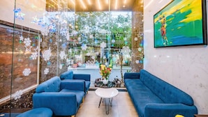 A modern lobby with blue sofas, a glass wall with snowflake decorations, and a large painting on the wall. - The Shann Hotel Da Nang (Da Nang)