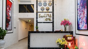 A hotel reception desk with a modern design, featuring a marble counter and a clock display showing multiple time zones. - The Shann Hotel Da Nang (Da Nang)