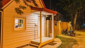 Een klein, laag gebouw met een veranda en een bord waarop staat: 'Kave House Backpackers'.