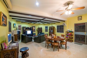 A living room with a dining area, a ceiling fan, and a TV.