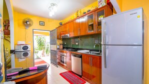 A compact kitchen with wooden cabinets, a white refrigerator, a stove, and a sink.