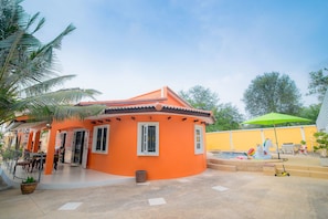 A house with an orange exterior, a swimming pool, and a green umbrella.