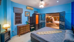 A bedroom with a bed, dresser, vanity, and a wardrobe with a mirror.