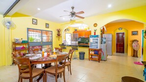 A dining area with a round table, chairs, and a ceiling fan.