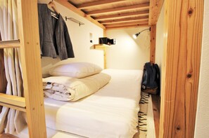 Une petite pièce agréable et chaleureuse, avec un lit, une armoire en bois et un porte-manteau mural.