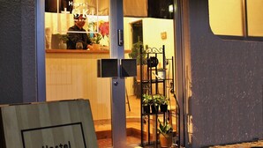Un hostal acogedor y pequeño con un letrero de madera, una recepción y plantas en macetas afuera.
