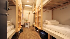 Habitación pequeña con literas, una mesita y una maleta.
