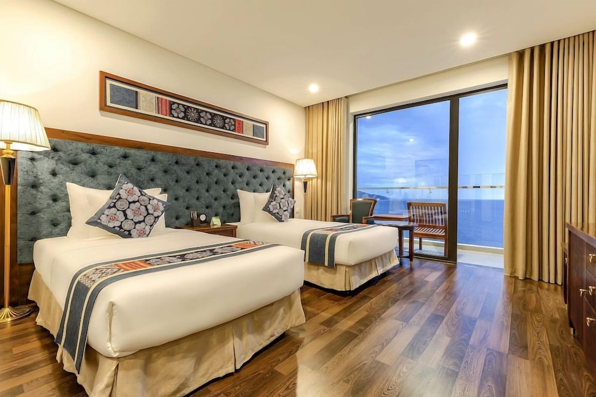 A hotel room with two beds, a balcony, and a view of the city.