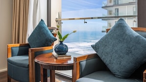 A room with a view of the ocean, featuring two chairs, a small table, and a vase with a plant. - Balcona Hotel Da Nang (Da Nang)