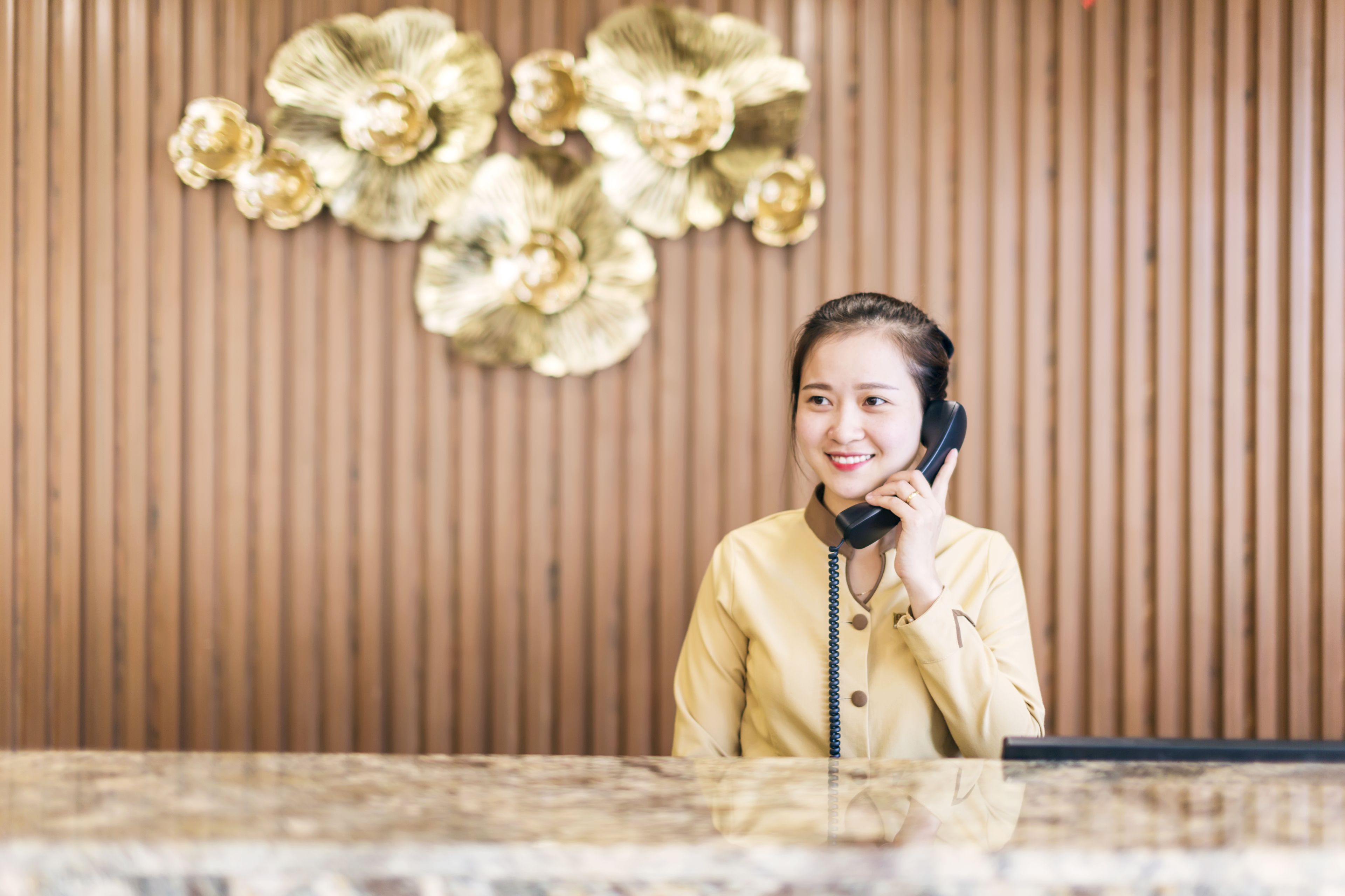 A reception area with a wooden panel wall and a decorative gold floral arrangement.
