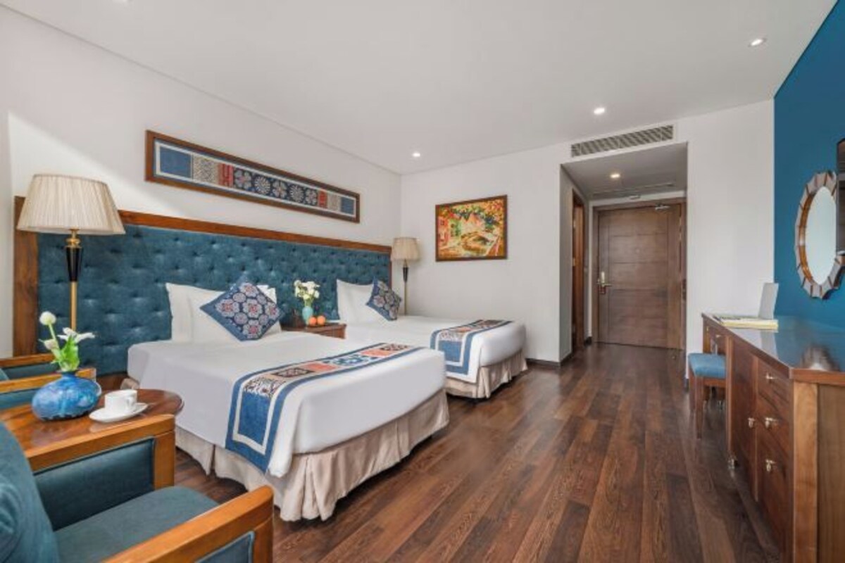 A hotel room with a large bed, two bedside tables, a desk, and a chair.