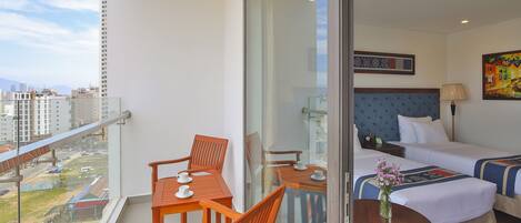 Una habitación de hotel con balcón, cama, escritorio y una silla.
