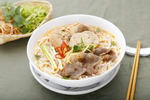 En skål nudelsuppe med kød og grøntsager.