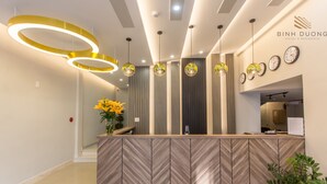 A reception area with a herringbone-patterned counter, modern pendant lighting, and a clock on the wall. - Binh Duong Resident Hotel (Da Nang)