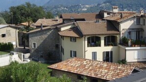 Un quartier résidentiel caractérisé par des toits recouverts de tuiles en terre cuite, des murs en pierre et un paysage montagneux en arrière-plan.