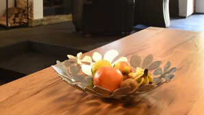 Un coin repas avec une table en bois, un saladier en métal et une cheminée en arrière-plan.