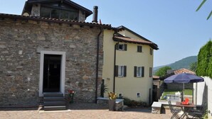 Il s’agit d’un bâtiment en pierre, doté d’une façade jaune et d’un toit recouvert de tuiles. On y trouve une terrasse aménagée avec du mobilier d’extérieur et une table.