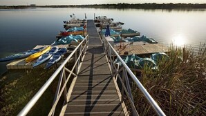 A wooden dock with kayaks and paddleboards, leading to calm water. - Orlando Condo (Orlando)