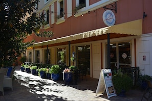 Un restaurante con terraza, plantas en macetas y un letrero.