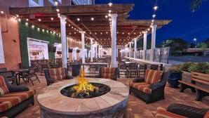 An outdoor patio area with a stone fire pit, seating, and string lights. - Orlando Condo (Orlando)
