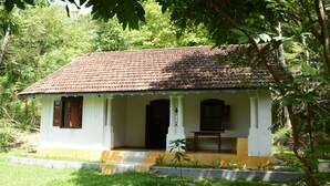 A small, single-story house with a tiled roof, a porch with a bench, and a small garden area. - Jungle house (Unawatuna)