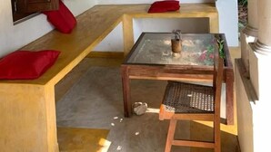 A corner room with a wooden bench, a small table with a glass top, and a wall-mounted door. - Jungle house (Unawatuna)