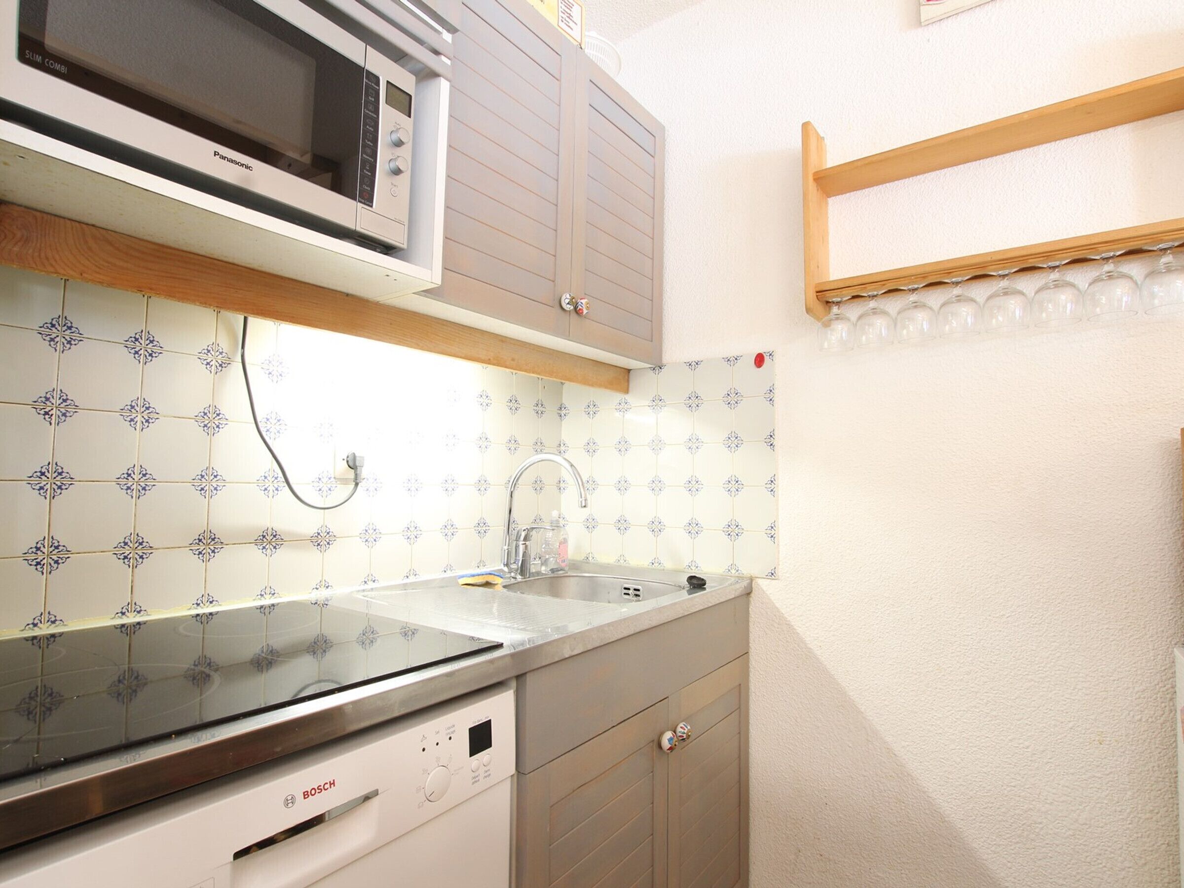 A compact kitchen with a Bosch dishwasher, a microwave, and a sink with a modern faucet.