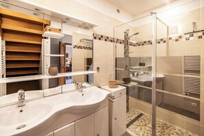 Un bagno moderno con cabina doccia in vetro, mobile lavabo doppio e specchio.