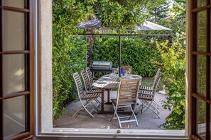 Un patio al aire libre con una mesa lista para comer, rodeado de vegetación.