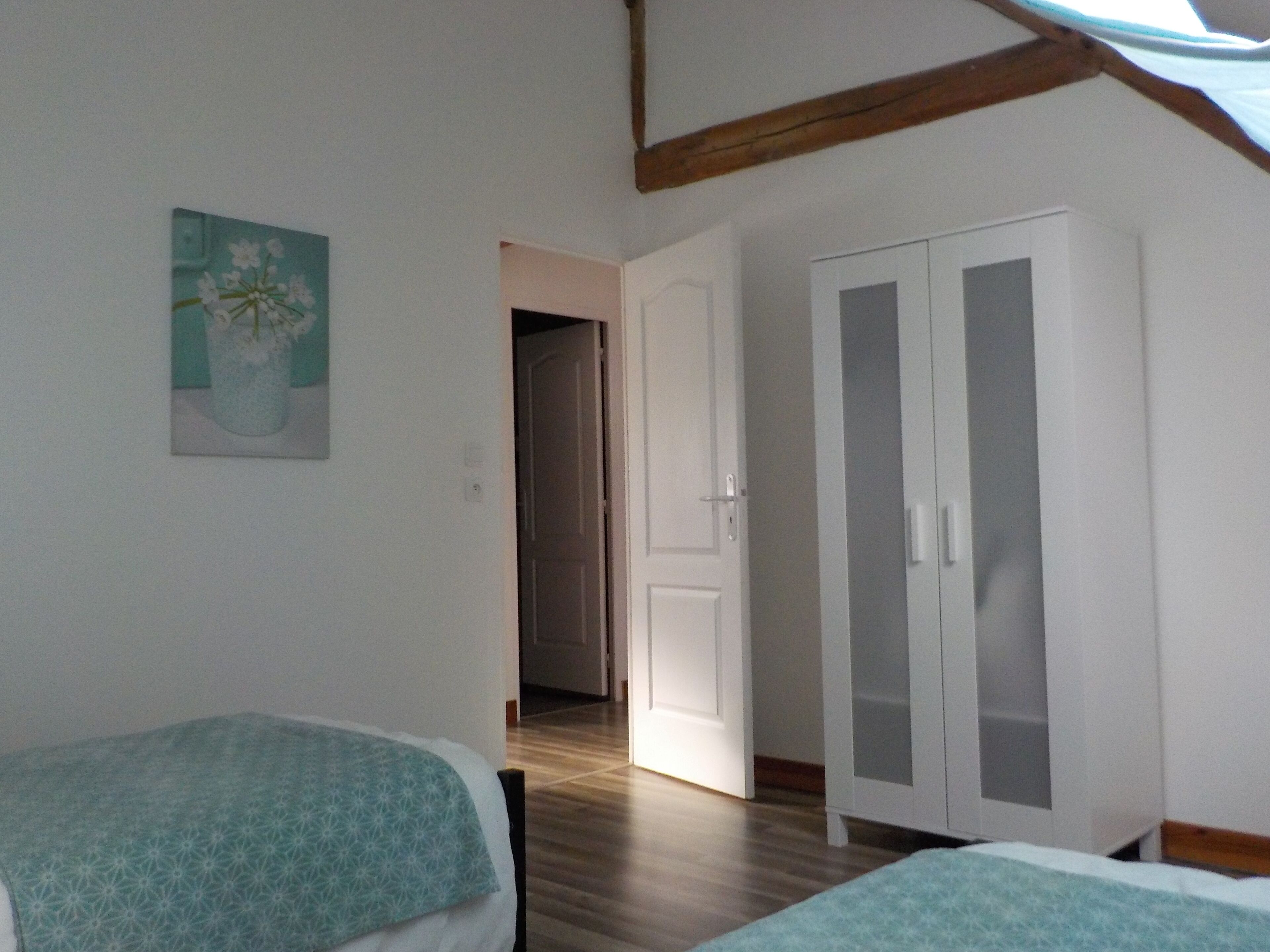A bedroom with a bed, a wardrobe, and a door leading to another room.