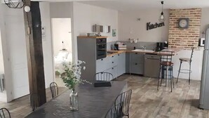 A modern kitchen with a central island, a dining table with chairs, and a refrigerator. - IDEAL FAMILY HOUSE (Bracieux)