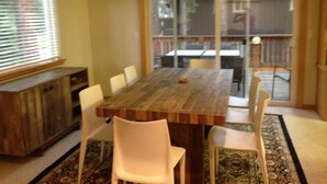 Un coin repas avec une table en bois, des chaises blanches et un tapis.